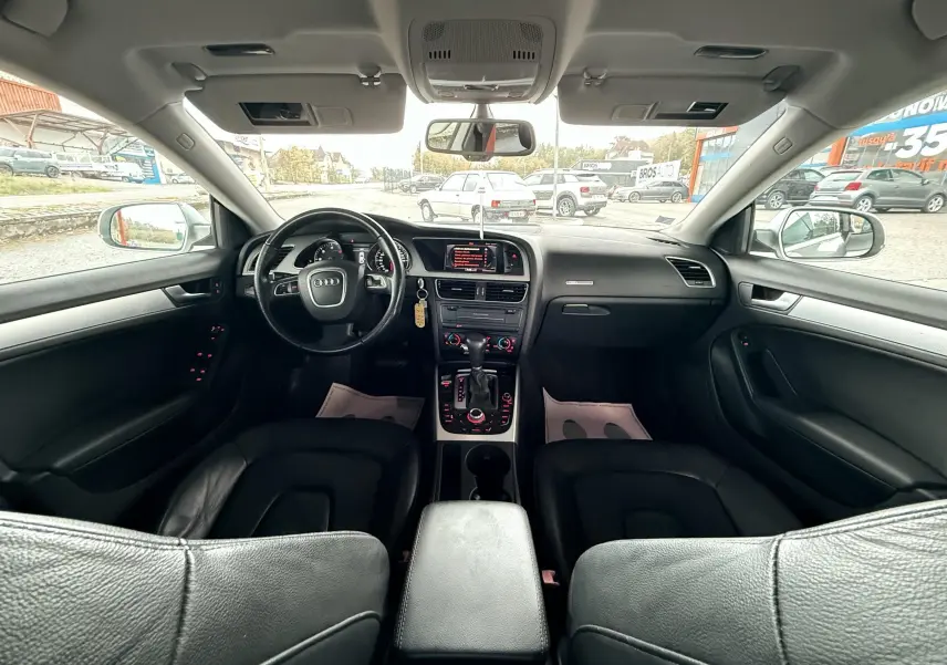 Intérieur noir de l'Audi A5 2011 vu de l'arrière, avec tableau de bord et console centrale détaillés.