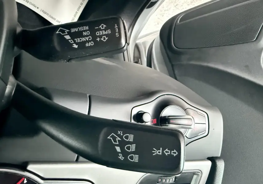 Gros plan sur les commandes d’éclairage et de clignotants d’une Audi A5 gris, côté gauche du volant.