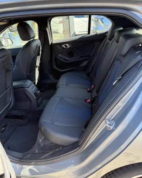 Vue intérieure côté droit montrant la banquette arrière en cuir noir de la BMW Série 1 118d Edition Sport gris foncé 2024.