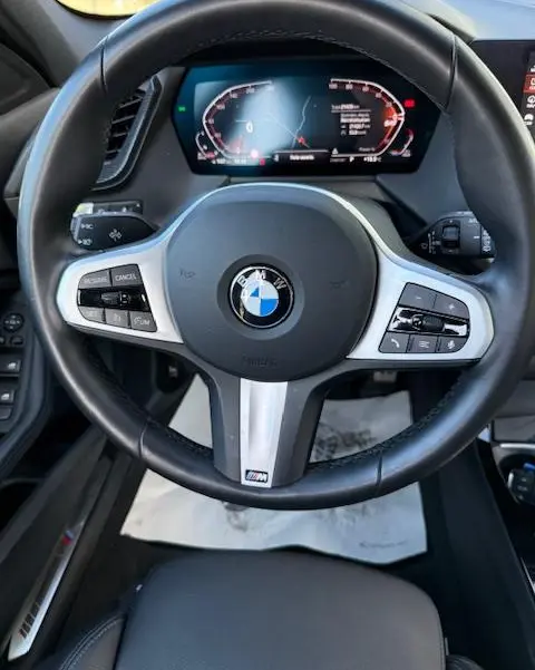 Vue rapprochée du volant cuir et alu d’une BMW Série 1 118d Edition Sport 2024 avec tableau de bord numérique.