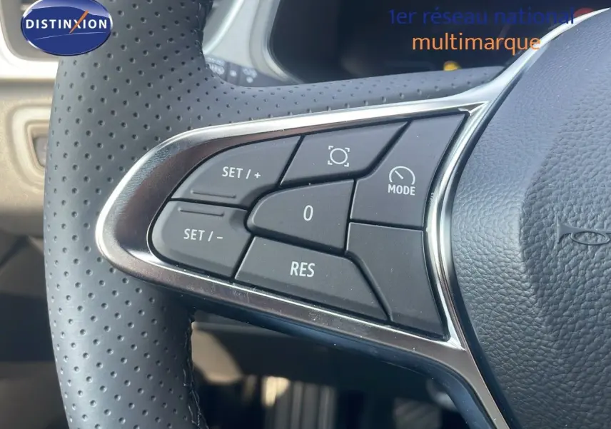 Gros plan sur les commandes du volant en cuir perforé du Renault Captur bleu Iron Metal, version mild hybrid 2025.