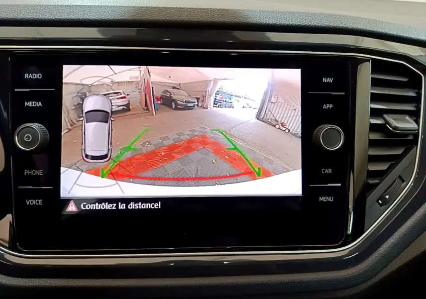 Écran tactile du Volkswagen T-Roc blanc montrant la caméra de recul avec guidage et alerte de distance.