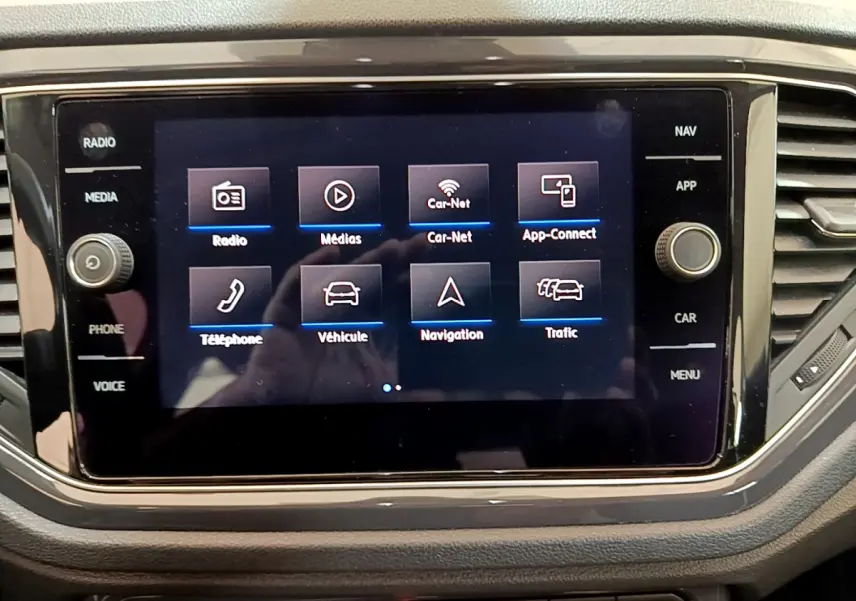 Écran tactile central du tableau de bord du Volkswagen T-Roc blanc, affichant le menu multimédia et navigation.