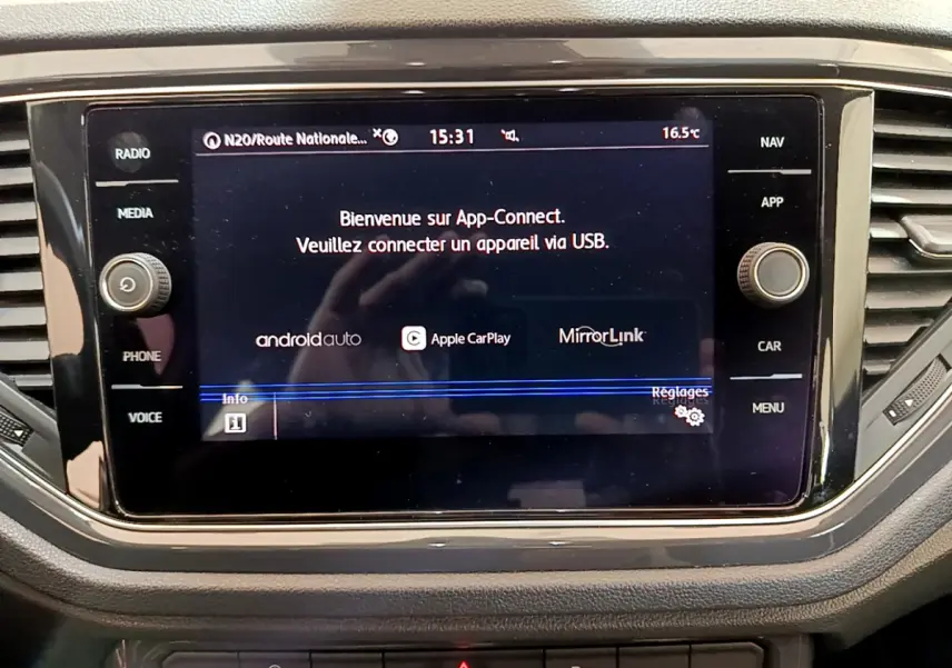 Écran tactile central du tableau de bord du Volkswagen T-Roc blanc, affichant App-Connect et options de connectivité.