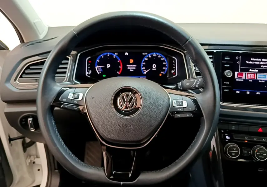 Vue rapprochée du volant cuir noir et du tableau de bord numérique du Volkswagen T-Roc blanc 2020.