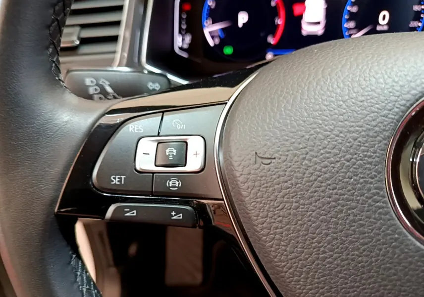 Gros plan sur le volant cuir du Volkswagen T-Roc blanc 2020, avec commandes de régulateur adaptatif visibles.