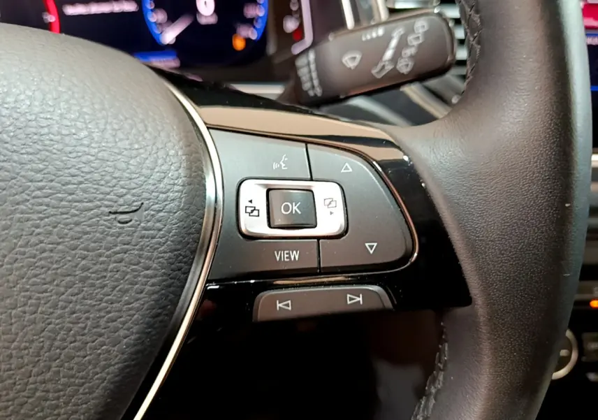 Gros plan sur les commandes à droite du volant cuir du Volkswagen T-Roc blanc, avec affichage numérique en arrière-plan.