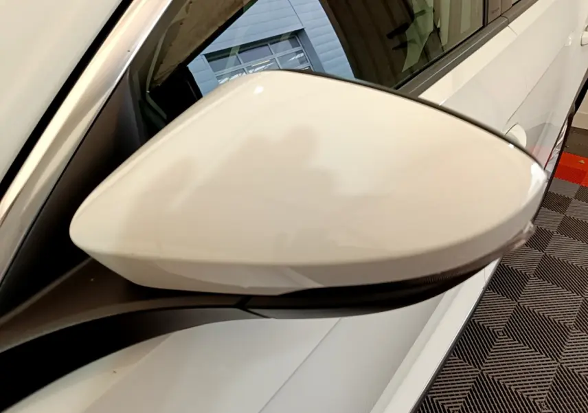 Gros plan sur le rétroviseur droit blanc d'un Volkswagen T-Roc 1.5 TSI 150 EVO Carat DSG7 2020, vue latérale.