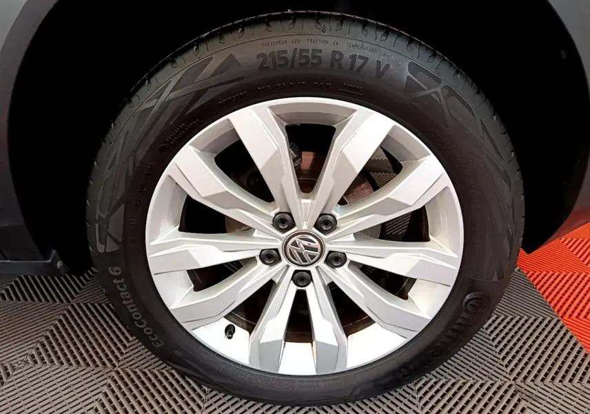 Gros plan sur la roue avant droite d'un Volkswagen T-Roc blanc avec jante alliage à dix branches.