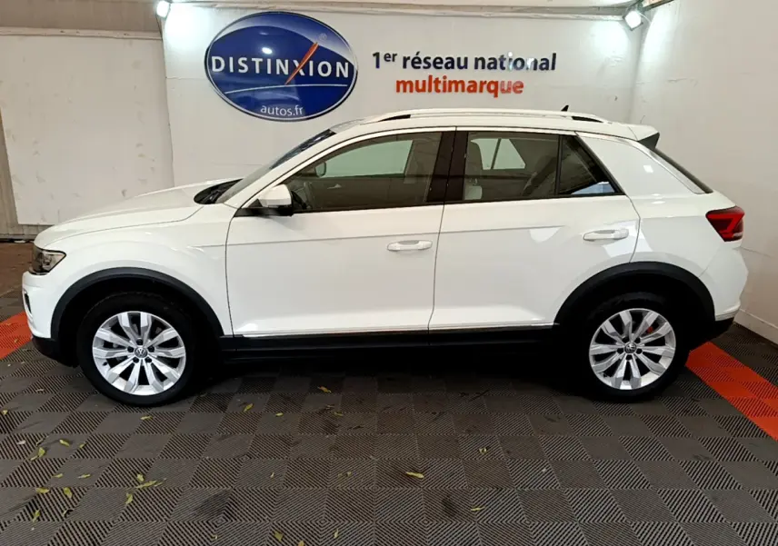 Profil droit d'un Volkswagen T-Roc blanc 2020, SUV compact avec jantes alliage et rails de toit chromés visibles.