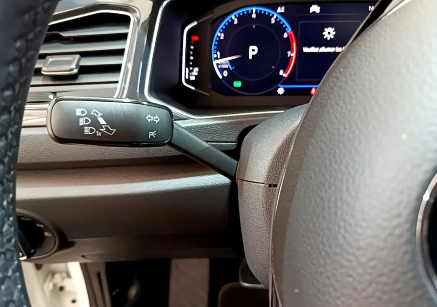 Gros plan sur le volant et le compteur digital du Volkswagen T-Roc 1.5 TSI blanc, affichant le mode parking.