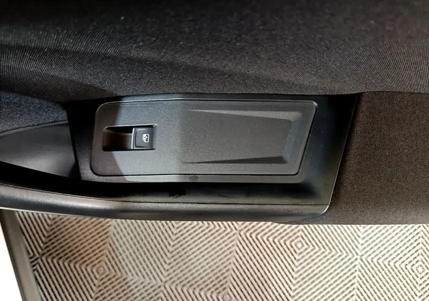 Gros plan sur le bouton de lève-vitre électrique côté conducteur du Volkswagen T-Roc blanc, intérieur noir.