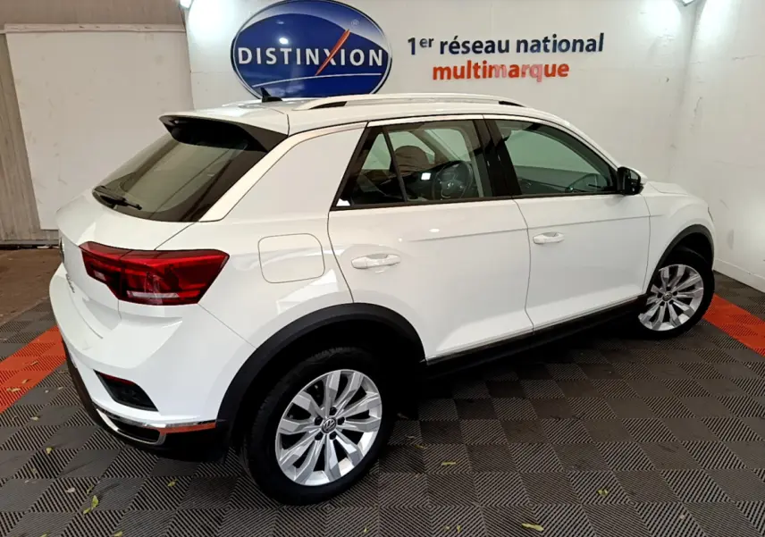 Volkswagen T-Roc blanc vu de trois quarts arrière droit, avec jantes alliage et toit ouvrant visible.