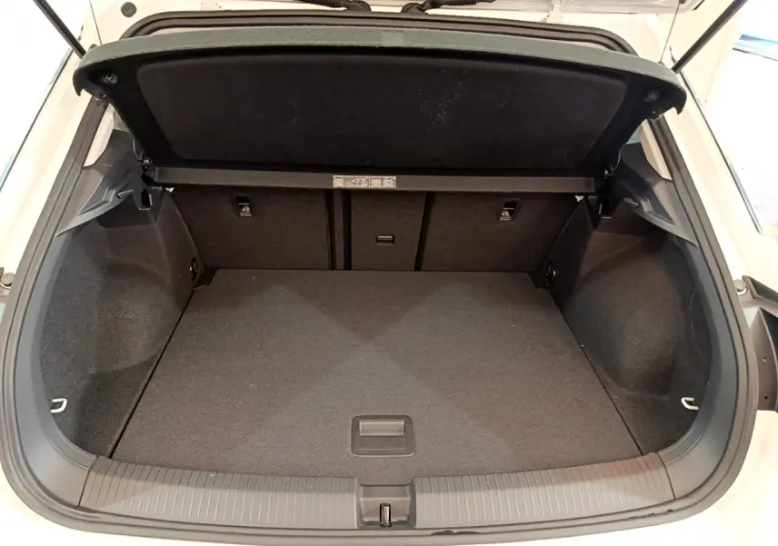 Coffre ouvert du Volkswagen T-Roc blanc, vue arrière montrant l'espace de chargement vide et la tablette de couverture.