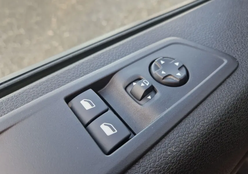 Gros plan sur les commandes de réglage des rétroviseurs et des vitres côté gauche du FIAT Scudo Fourgon blanc 2024.