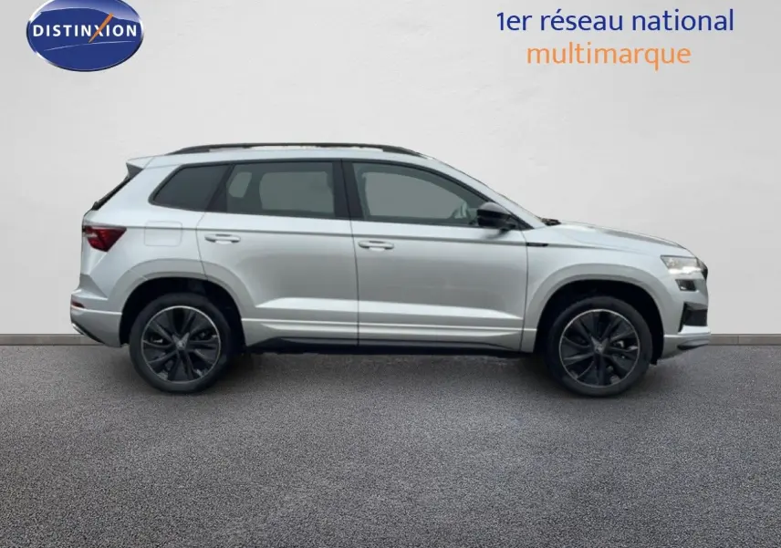 Vue latérale droite d'un Skoda Karoq gris argent métallisé 2025 avec jantes noires et toit ouvrant.