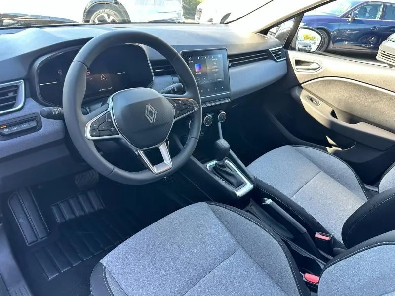 Vue intérieure côté conducteur de la Renault Clio 2025 avec volant multifonction, écran tactile et sièges gris motif 3D.