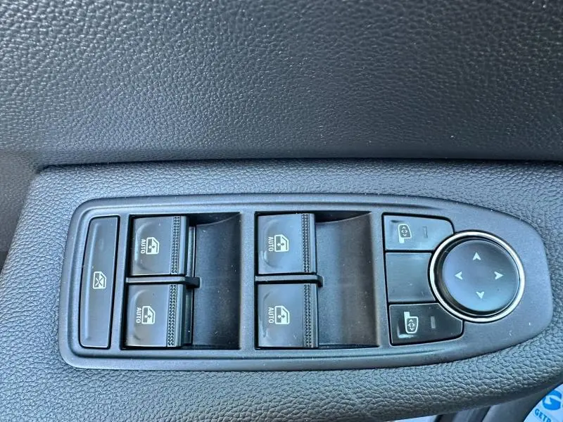 Gros plan sur les commandes de lève-vitres et réglage des rétroviseurs côté conducteur, finition noire texturée.