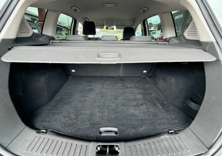 Vue du coffre arrière ouvert du Ford Kuga blanc de 2012, montrant l'espace de chargement avec cache-bagages déployé.