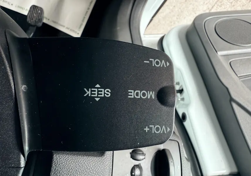 Gros plan sur la commande de volume et mode audio du Ford Kuga 2.0 TDCI blanc, côté conducteur intérieur.