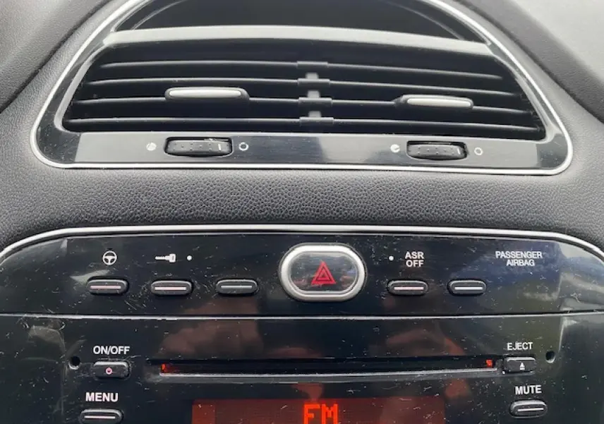 Tableau de bord de Fiat Grande Punto 2015 en gros plan, avec commandes radio et ventilation visibles.