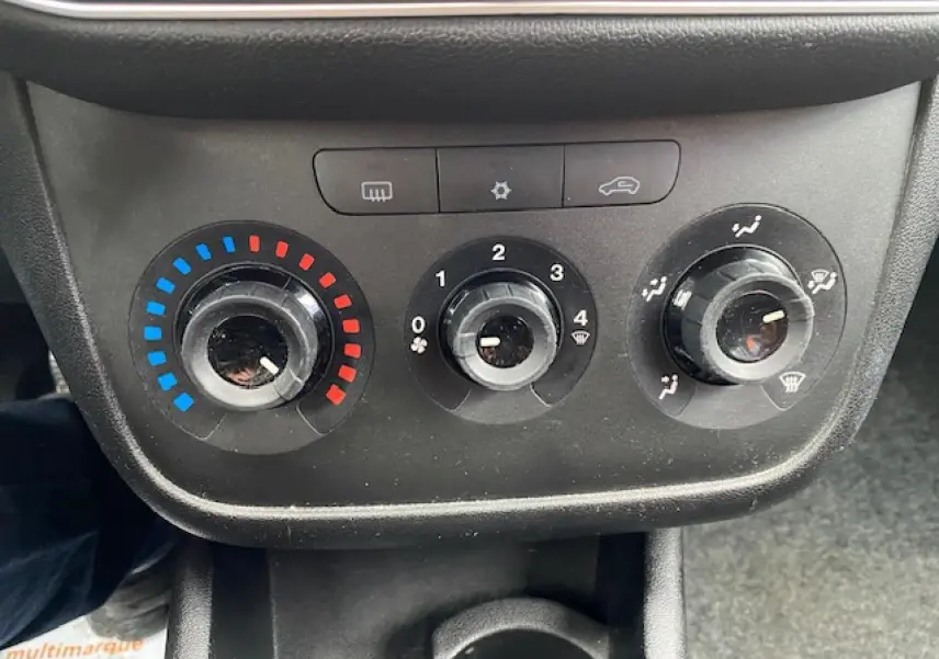 Tableau de commande de climatisation manuel noir d'une Fiat Grande Punto gris, avec réglages température, ventilation et air.