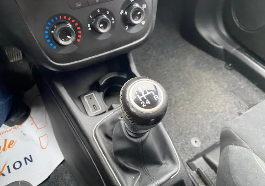Gros plan sur le levier de vitesse manuel et les commandes de climatisation d'une Fiat Grande Punto gris métallisé.