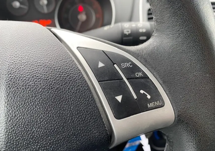 Gros plan sur les commandes au volant de la Fiat Grande Punto gris métallisé, avec boutons SRC, OK et menu visibles.