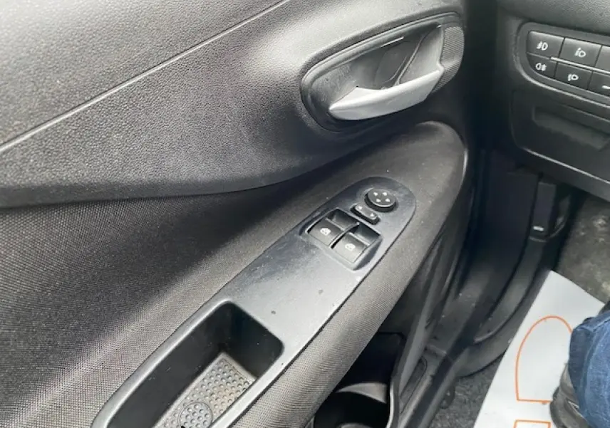 Gros plan sur la porte côté conducteur de la Fiat Grande Punto gris, montrant les commandes des vitres électriques et la poignée intérieure.