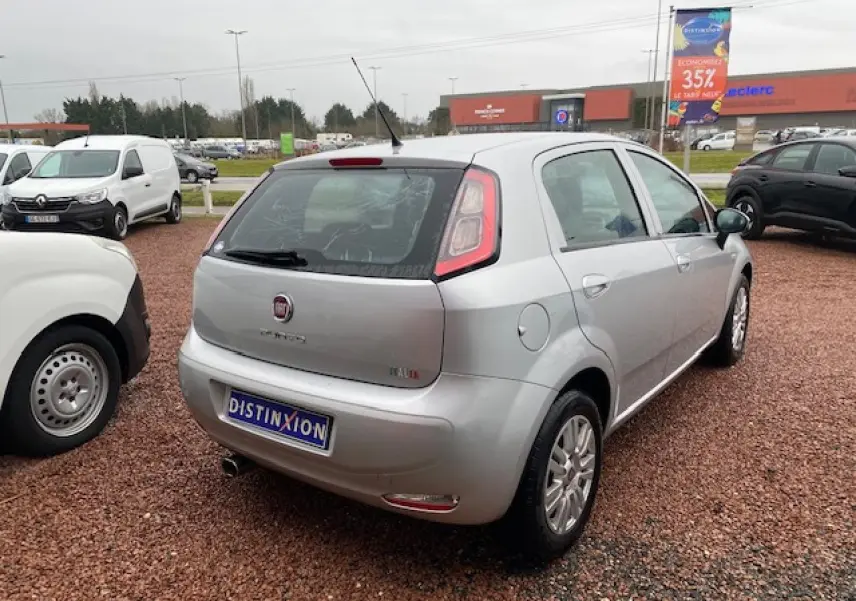 Vue 3/4 arrière droite d'une Fiat Grande Punto gris métallisé, avec feux arrière caractéristiques et antenne de toit.