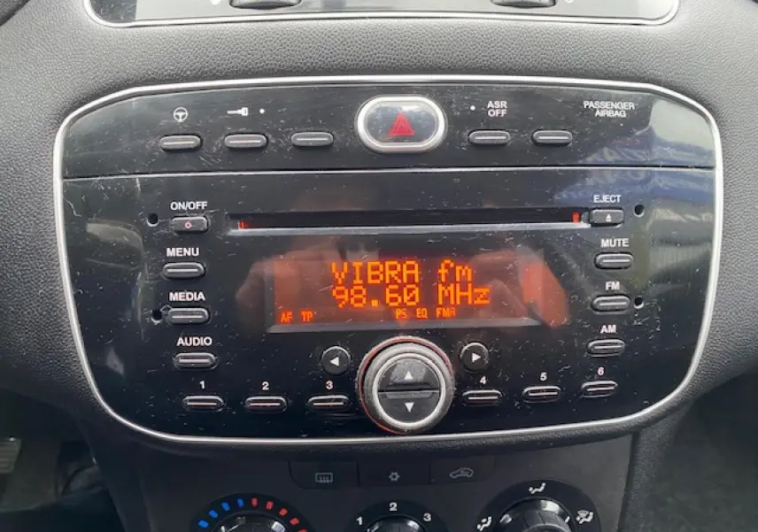 Gros plan sur la radio CD MP3 intégrée du tableau de bord d'une Fiat Grande Punto gris métallisé, affichant la station VIBRA fm.