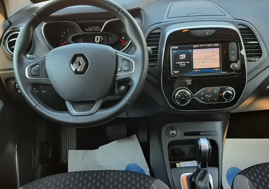 Vue intérieure frontale du tableau de bord du Renault Captur 2019 avec volant noir et écran tactile central allumé.
