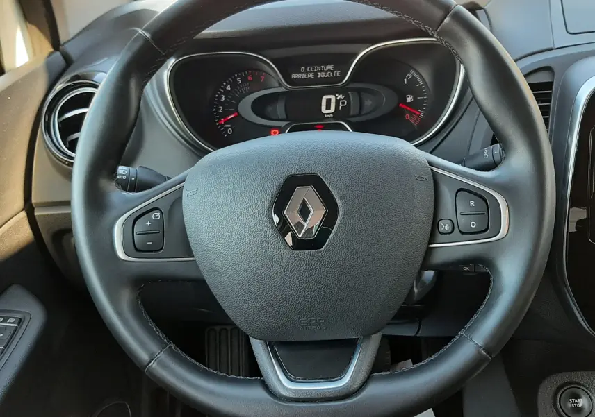 Vue intérieure centrée sur le volant noir du Renault Captur 2019 avec tableau de bord numérique et commandes intégrées.