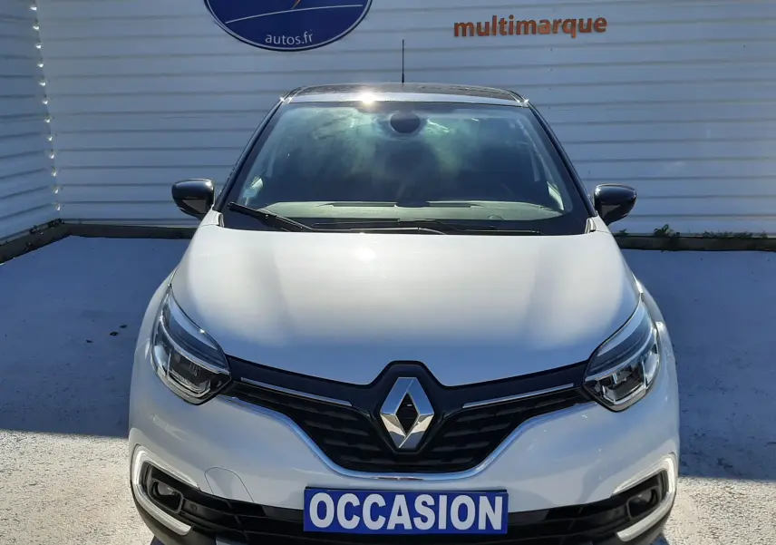 Vue frontale d'un Renault Captur blanc nacré avec toit noir, calandre noire et plaque "OCCASION" visible.
