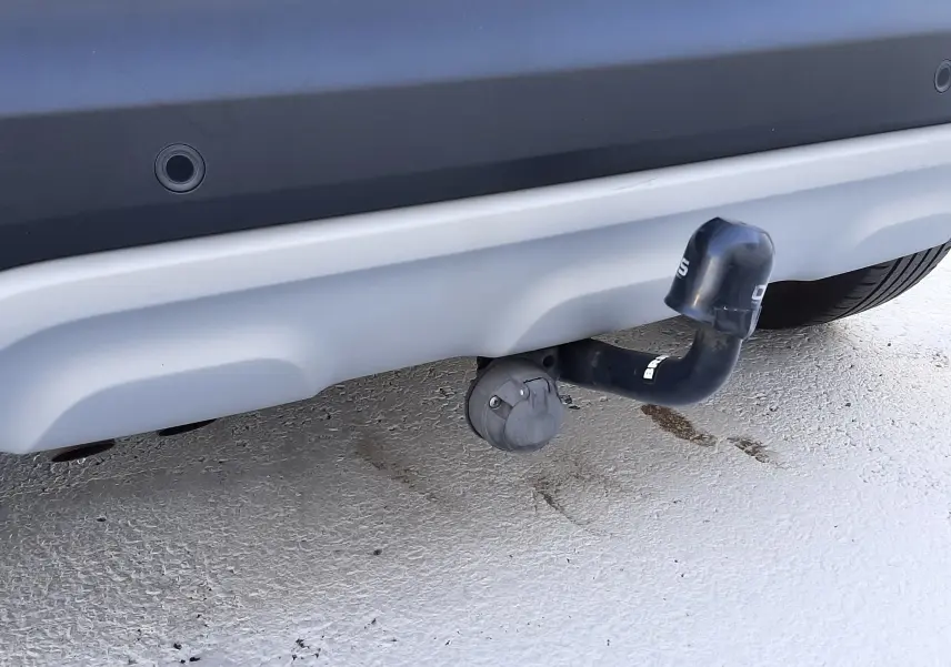 Gros plan sur l'attelage de remorque sous le pare-chocs arrière gris d'un Renault Captur blanc nacré avec toit noir.