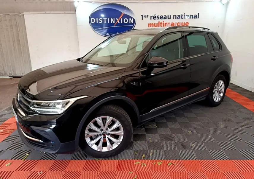 Volkswagen Tiguan noir 2021 vu en 3/4 avant droit dans un showroom avec sol noir et rouge.