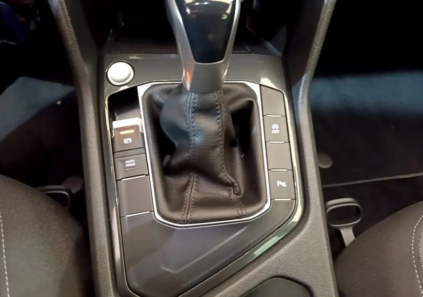 Gros plan sur la console centrale noire du Volkswagen Tiguan 2021, mettant en valeur le levier de vitesse automatique et les boutons de commande.