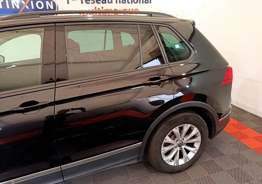 Vue latérale côté droit du Volkswagen Tiguan noir 2021, mettant en valeur la roue arrière et la carrosserie brillante.