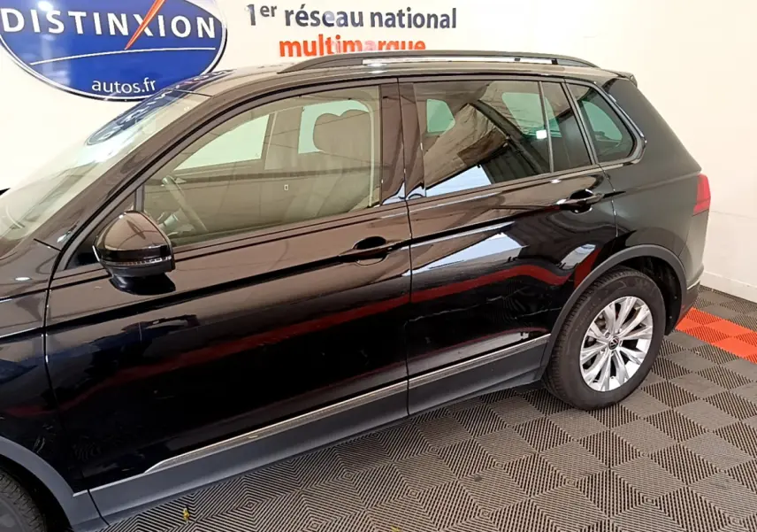 Vue latérale droite d'un Volkswagen Tiguan noir 2021 stationné en intérieur sur sol à damier rouge et noir.