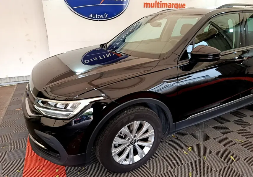 Vue 3/4 avant côté gauche d'un Volkswagen Tiguan noir brillant avec jantes alliage et phares LED.