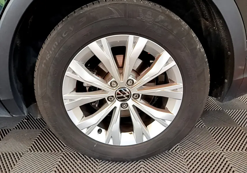 Gros plan sur la roue avant gauche du Volkswagen Tiguan noir, mettant en valeur la jante alliage argentée à 10 branches.