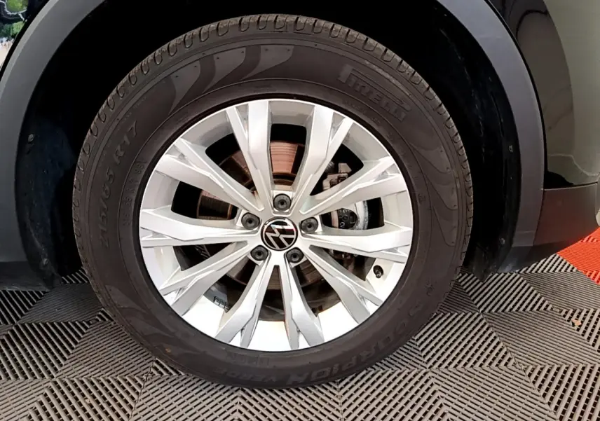 Gros plan sur la roue avant gauche du Volkswagen Tiguan noir 2021, jante alliage 17 pouces avec logo VW central.