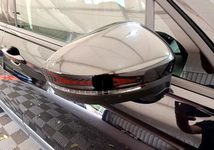 Gros plan sur le rétroviseur côté conducteur noir brillant du Volkswagen Tiguan 2.0 TDI 150 DSG7 Life Business.