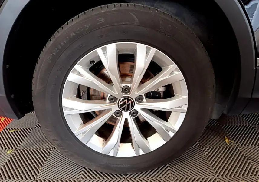 Gros plan sur la roue avant droite du Volkswagen Tiguan noir, mettant en valeur la jante argentée au design moderne.