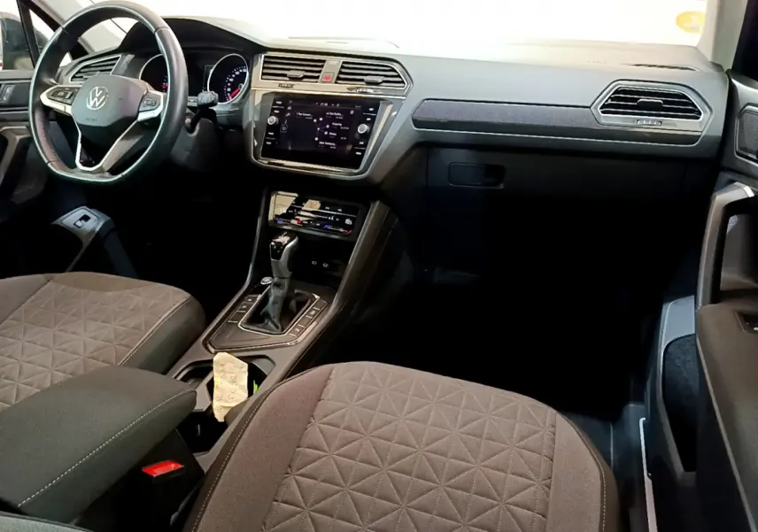 Intérieur avant du Volkswagen Tiguan 2.0 TDI 2021, vue du côté conducteur avec tableau de bord et console centrale noirs.