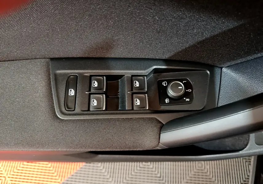 Vue rapprochée des commandes de lève-vitres et réglage des rétroviseurs côté conducteur du Volkswagen Tiguan noir.