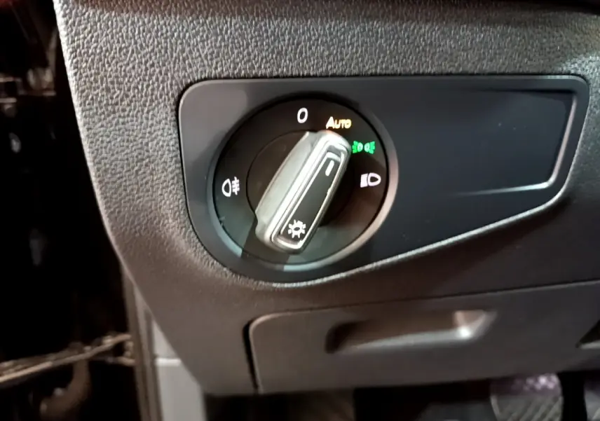 Gros plan sur le bouton de commande des phares du Volkswagen Tiguan noir, avec réglage automatique activé.