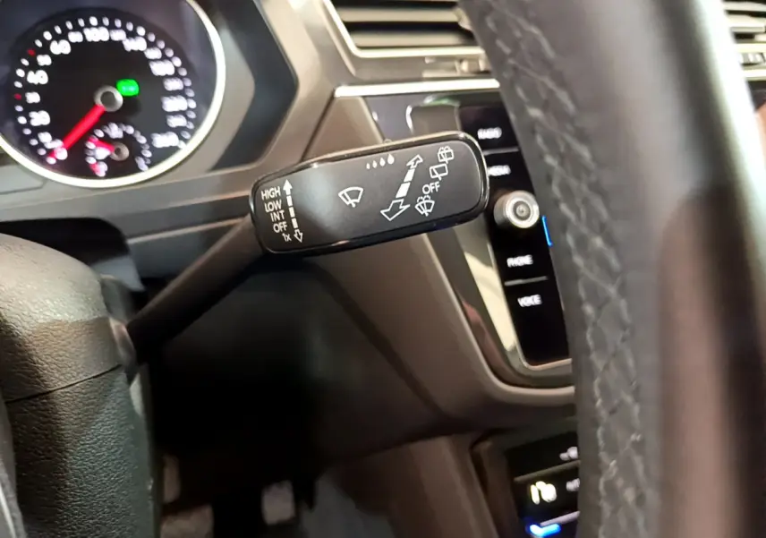 Gros plan sur le commodo d'essuie-glace à gauche du volant cuir dans l'habitacle noir du Volkswagen Tiguan 2021.