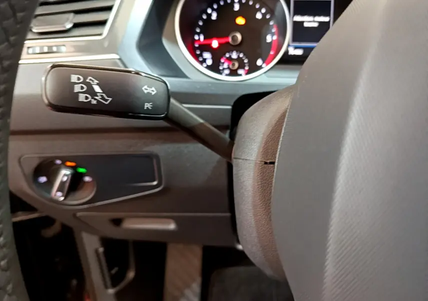 Gros plan sur le commodo gauche et le tableau de bord noir du Volkswagen Tiguan 2.0 TDI 2021 avec compteur analogique rouge et blanc.