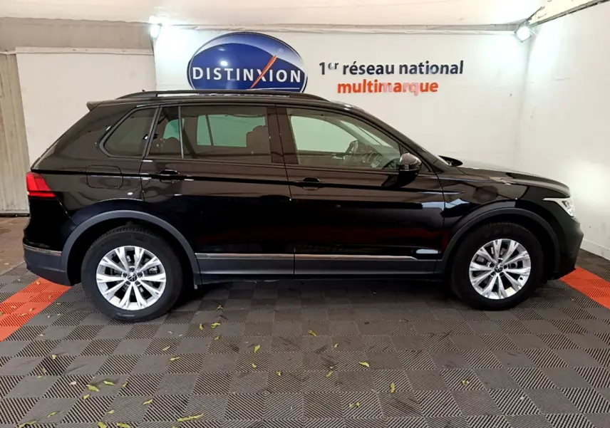 Vue latérale droite d'un Volkswagen Tiguan noir 2021 garé en intérieur avec jantes argentées et vitres teintées.